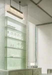 A well-organized bathroom with a green glass shelf holding various cups and bowls, creating a functional and tidy space