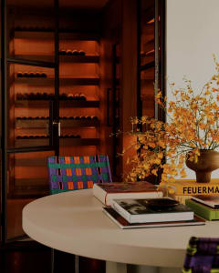 A cozy living space with a dining table, chairs, books, and a vase of flowers, creating a warm and inviting atmosphere