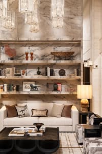 Cozy living room with a marble wall, a marble coffee table, a couch, a chair, and a bookshelf, decorated with books and a vase