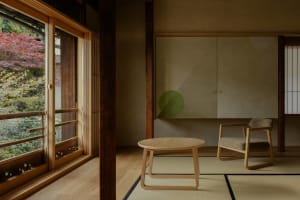 A modern living space with a wooden floor and table, a white wall, and natural light from a window