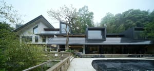 Modern luxury villa with black marble infinity pool in a lush mountain courtyard setting, surrounded by bamboo and trees.