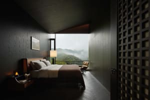 Modern dark wood bedroom interior featuring a large bed with neutral linens, a floor lamp, and a wide opening revealing a misty mountain and forest view.