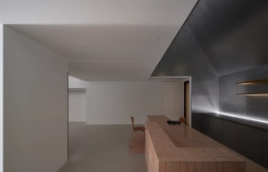 Modern minimalist hallway featuring a pinkish terrazzo floor, a long oak console on the left, and dramatic hidden LED strip lighting along the floor-wall junction.