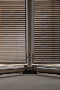 Close-up of a stainless steel T-joint connecting vertical and horizontal structural members with visible bolts and precision machining.