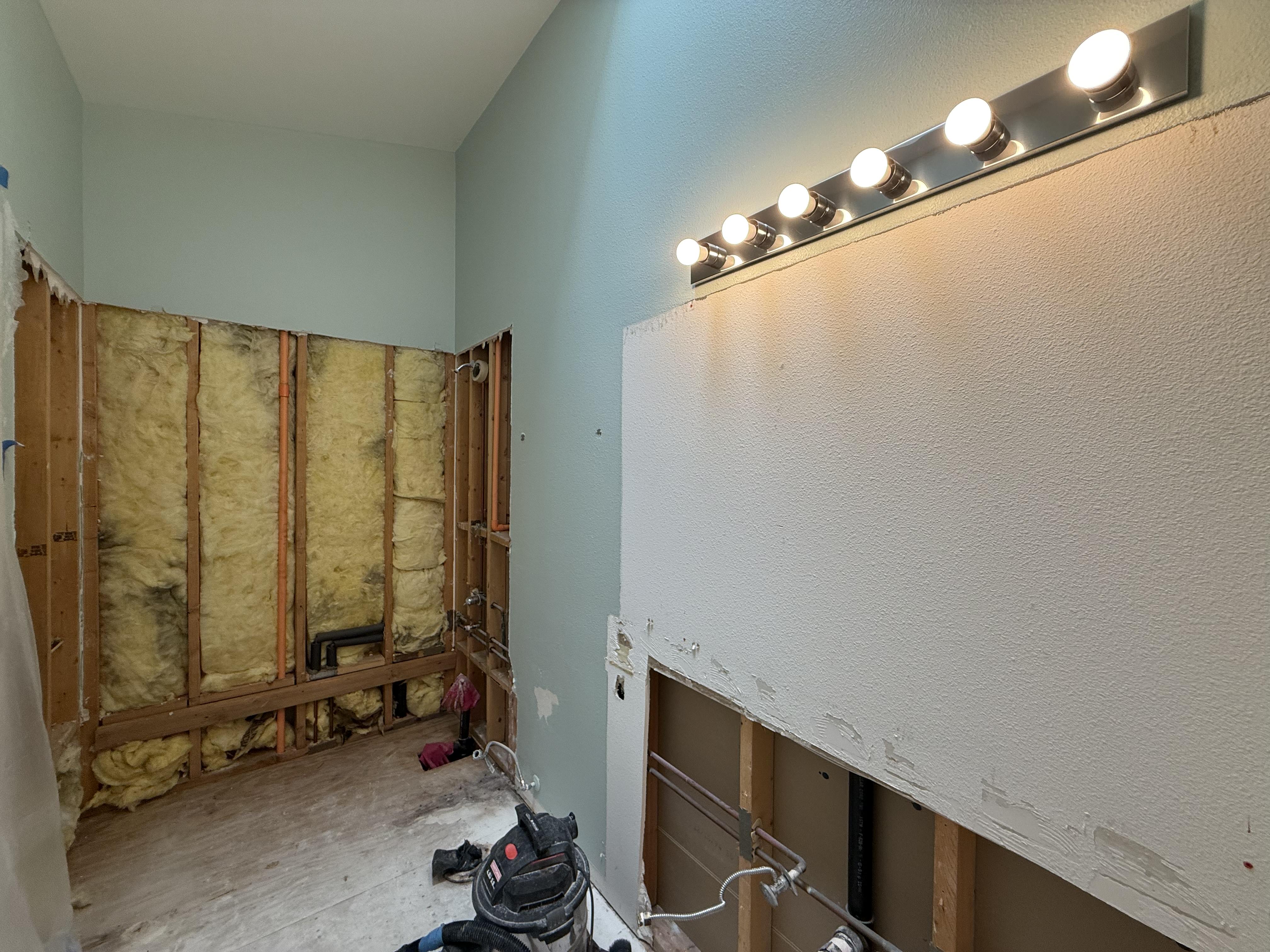 Before: 4×4 white tile surround, tiled counter with oak edge, sea-foam walls, mirror with Hollywood bar