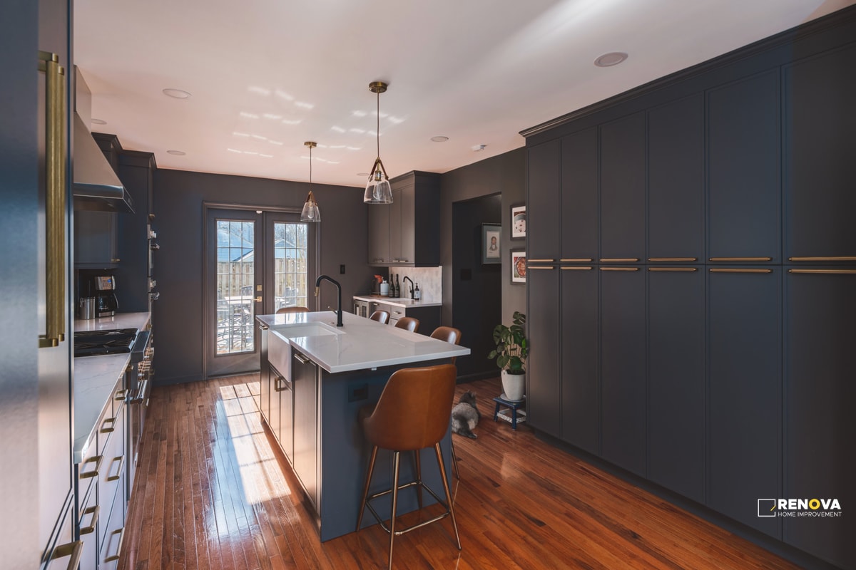 Modern kitchen remodeling Bellevue with dark cabinets, white countertop island, leather chairs, pendant lighting, and natural light - professional kitchen remodel specialists.