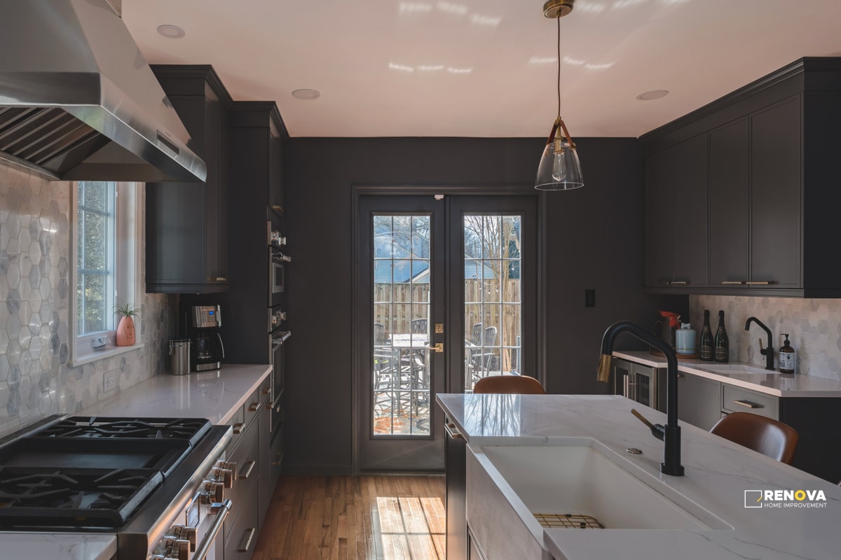 Modern kitchen remodel Bellevue with dark cabinetry, white countertops, large island with sink, stainless appliances, and patio access - kitchen renovation specialists.