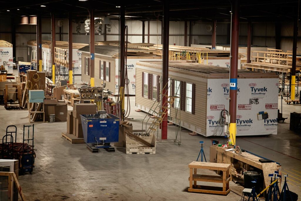 Bird's eyeview of a Modular home factory with various machines and several modules under construction
