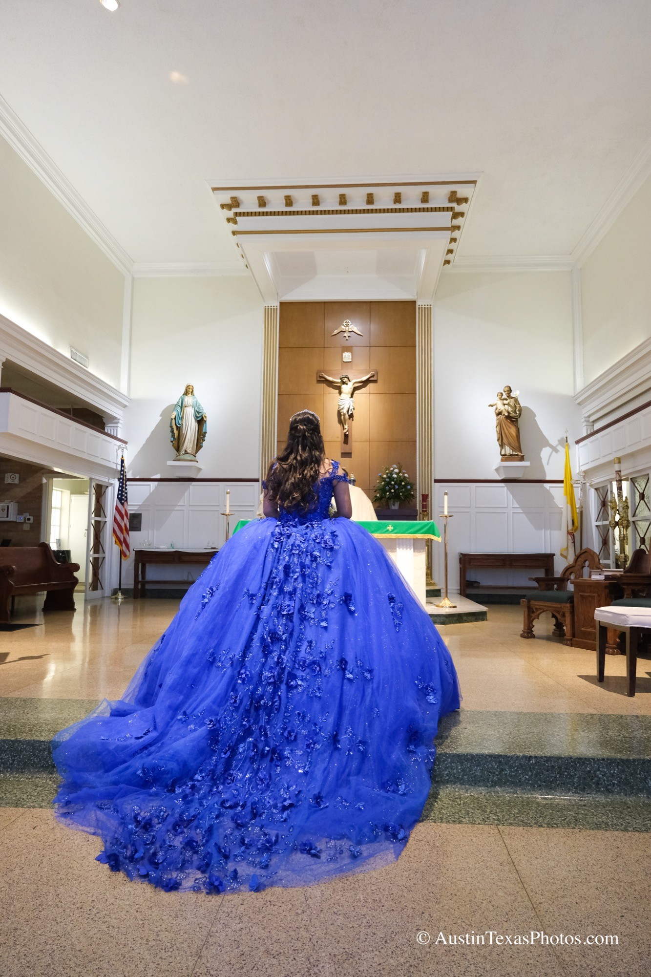 Quinceañera photographed from behind while looking toward the altar and Jesus crucifix