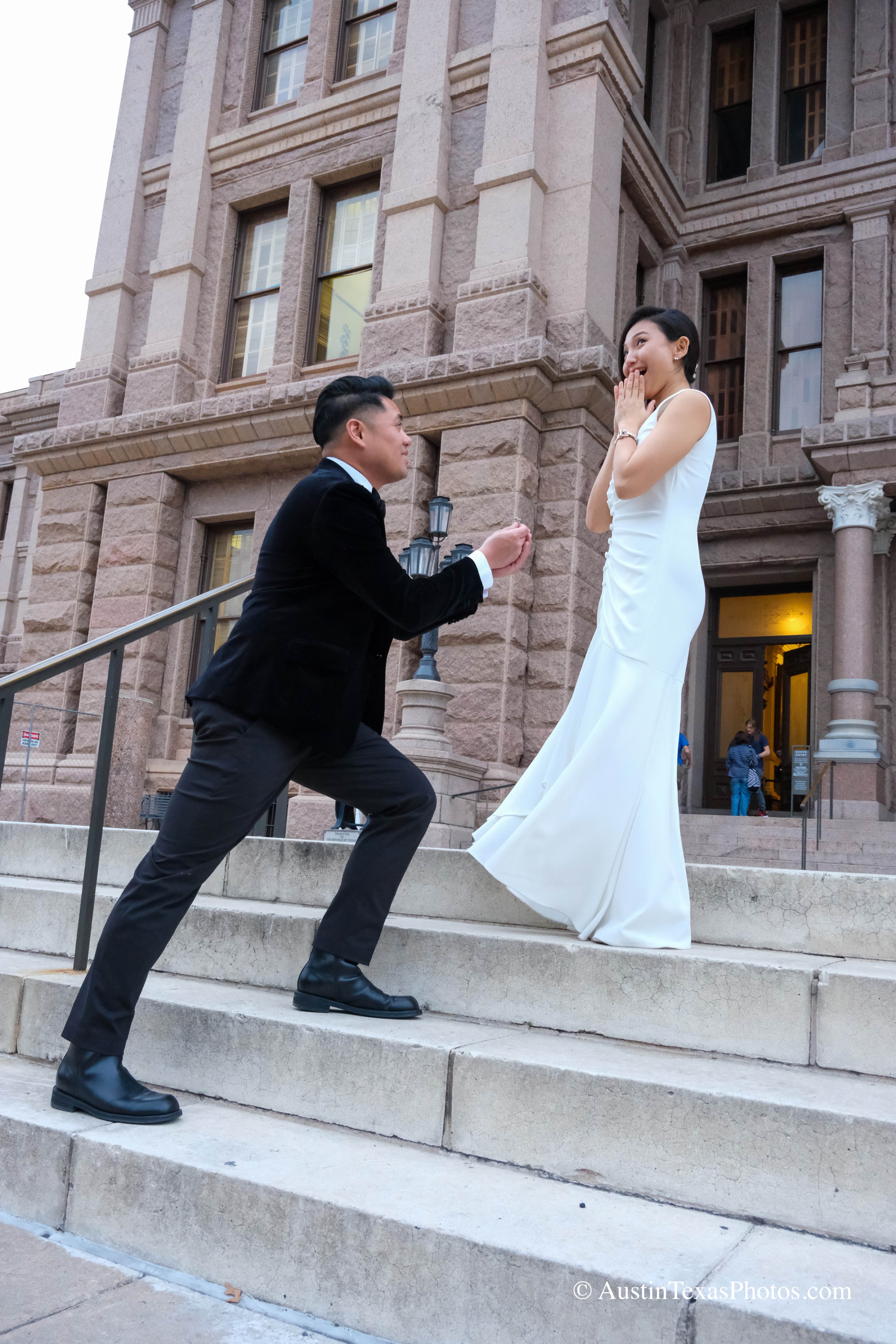 Groom on one knee proposing to bride on the Texas State Capitol stairs, Austin, Texas