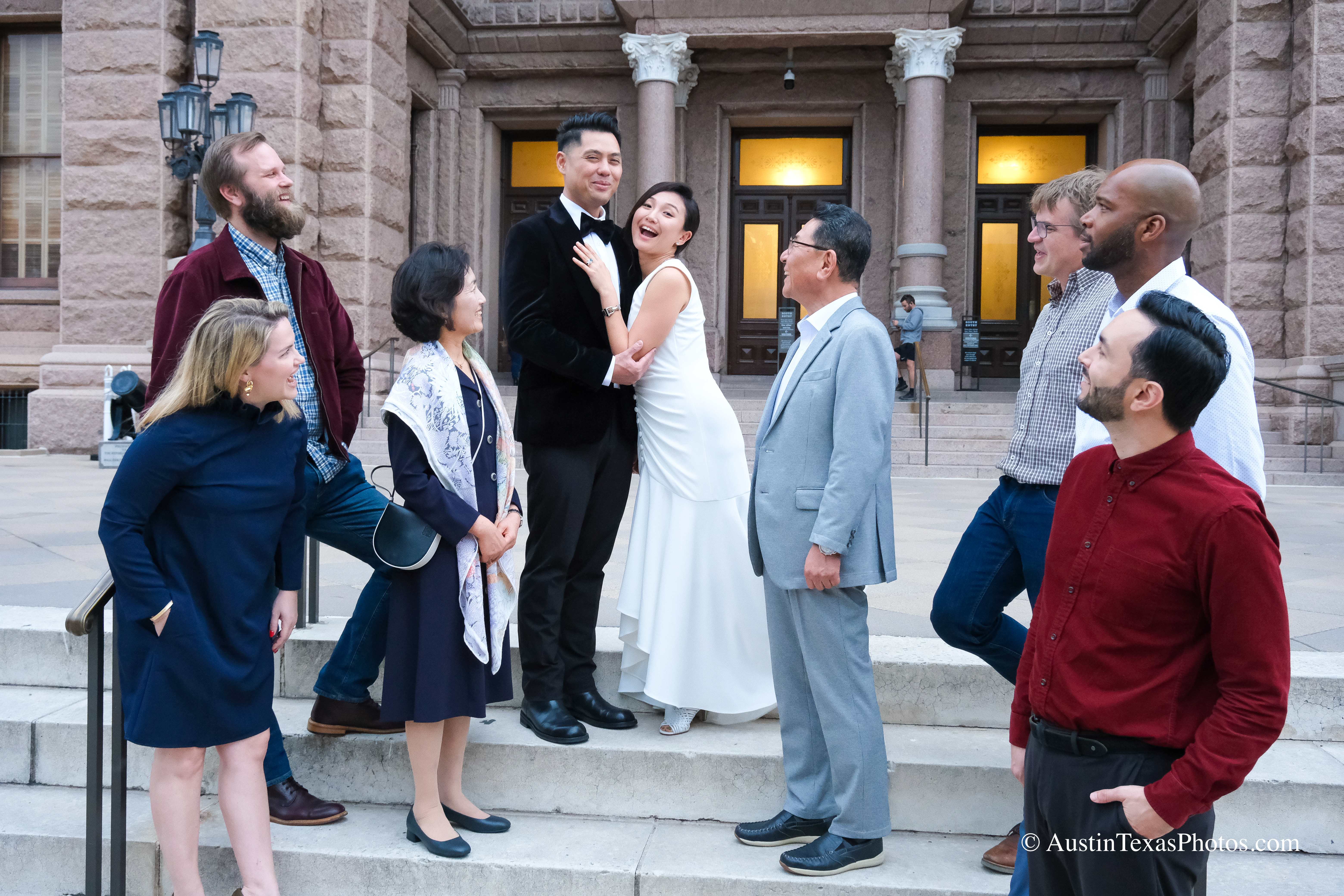 Bride and groom laughing on the Capitol stairs while family smiles, Austin, Texas