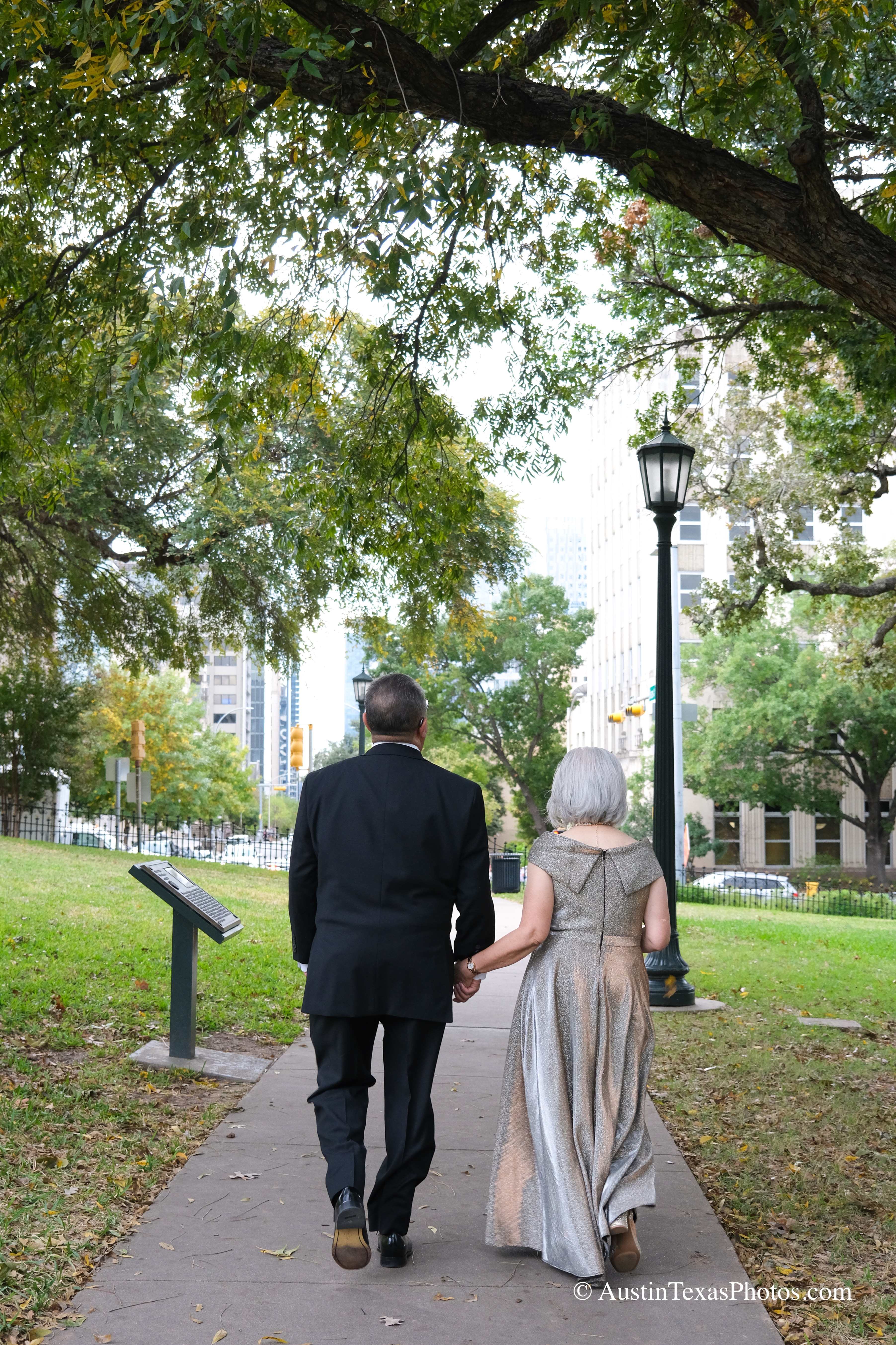 Bride and groom walking away together on the Texas State Capitol grounds, Austin, Texas