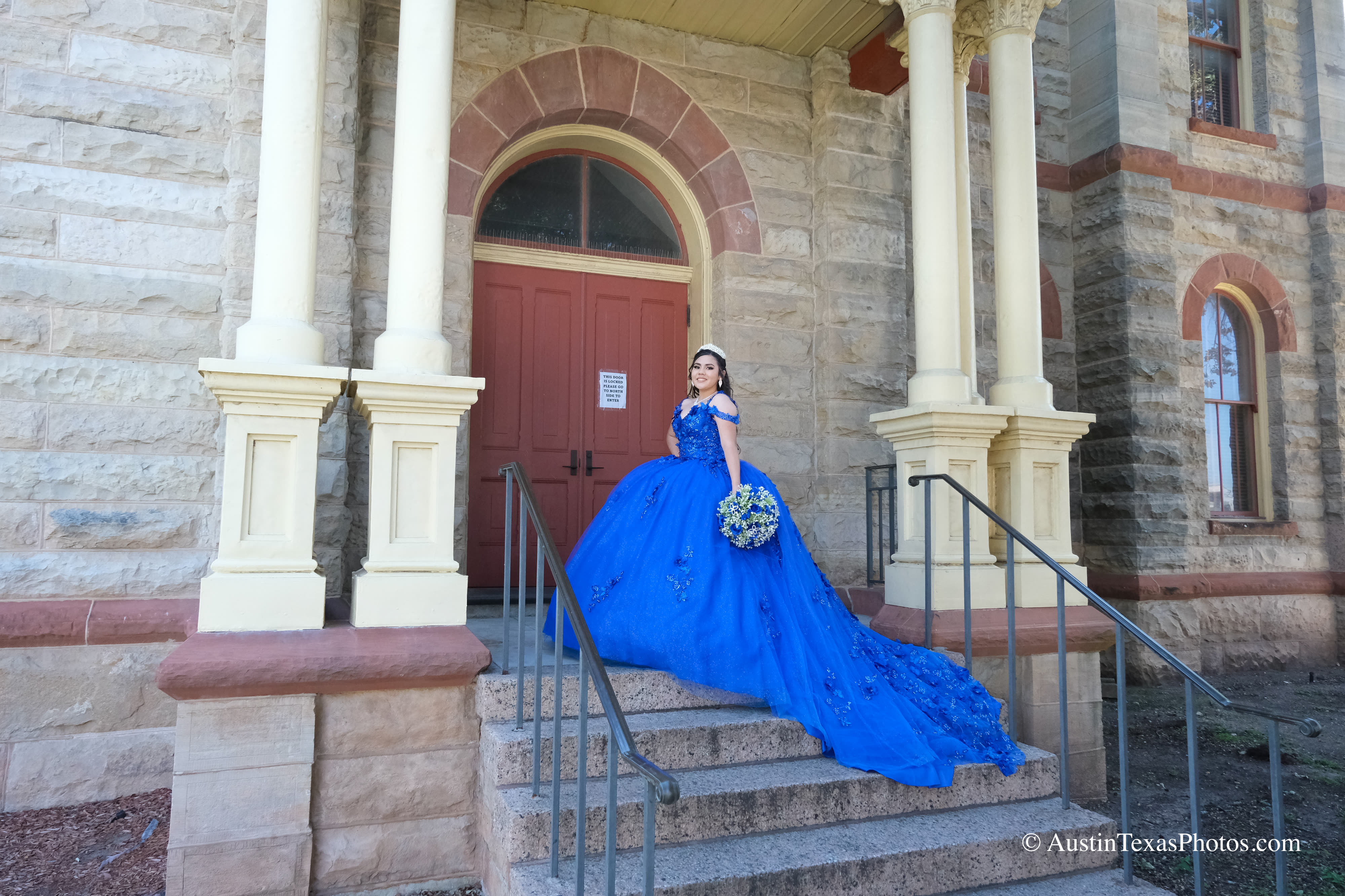 Quinceañera in royal blue gown on the steps of the Caldwell County Courthouse in Lockhart, Texas
