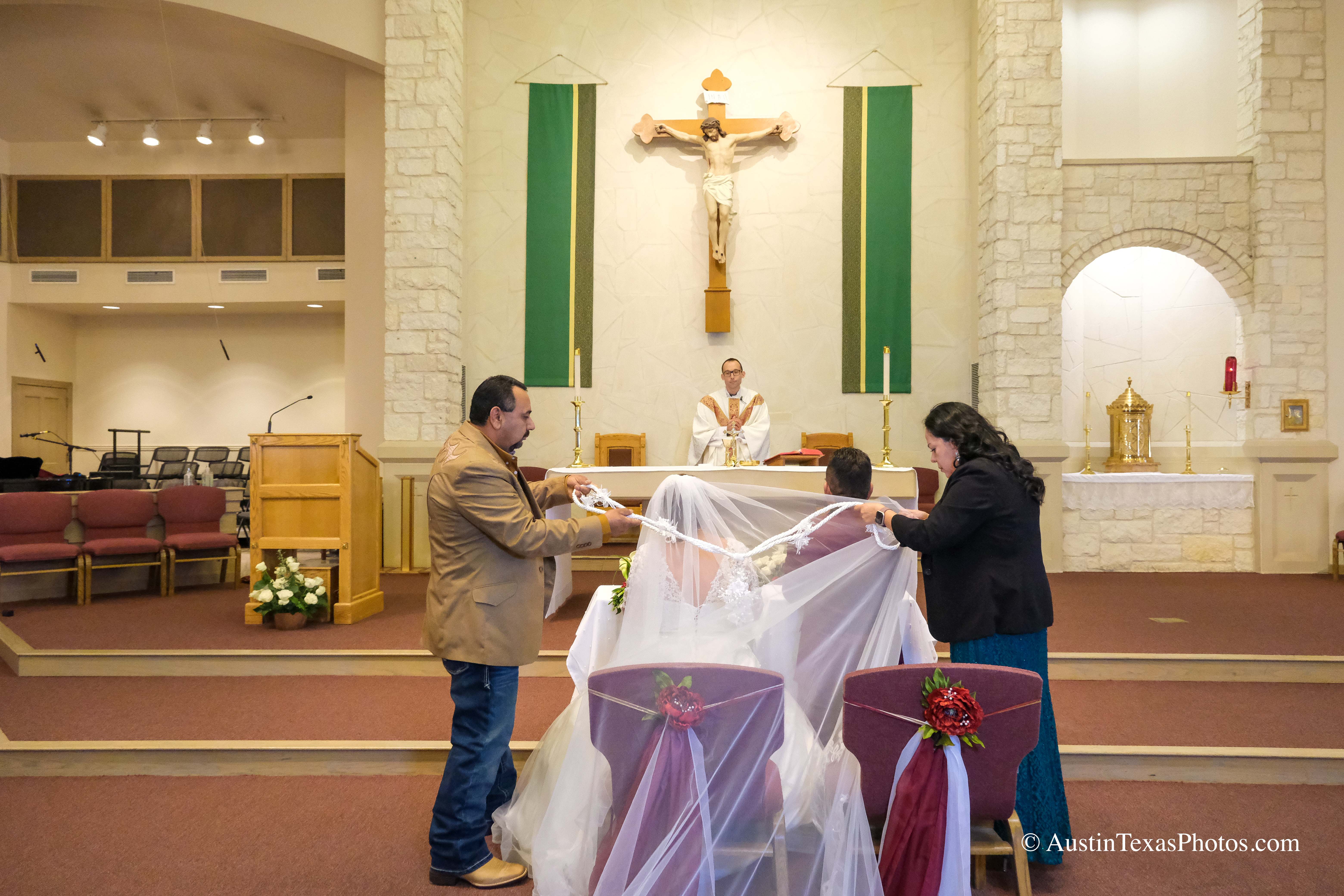 Bride and groom joined by lazo cord during Catholic wedding ceremony