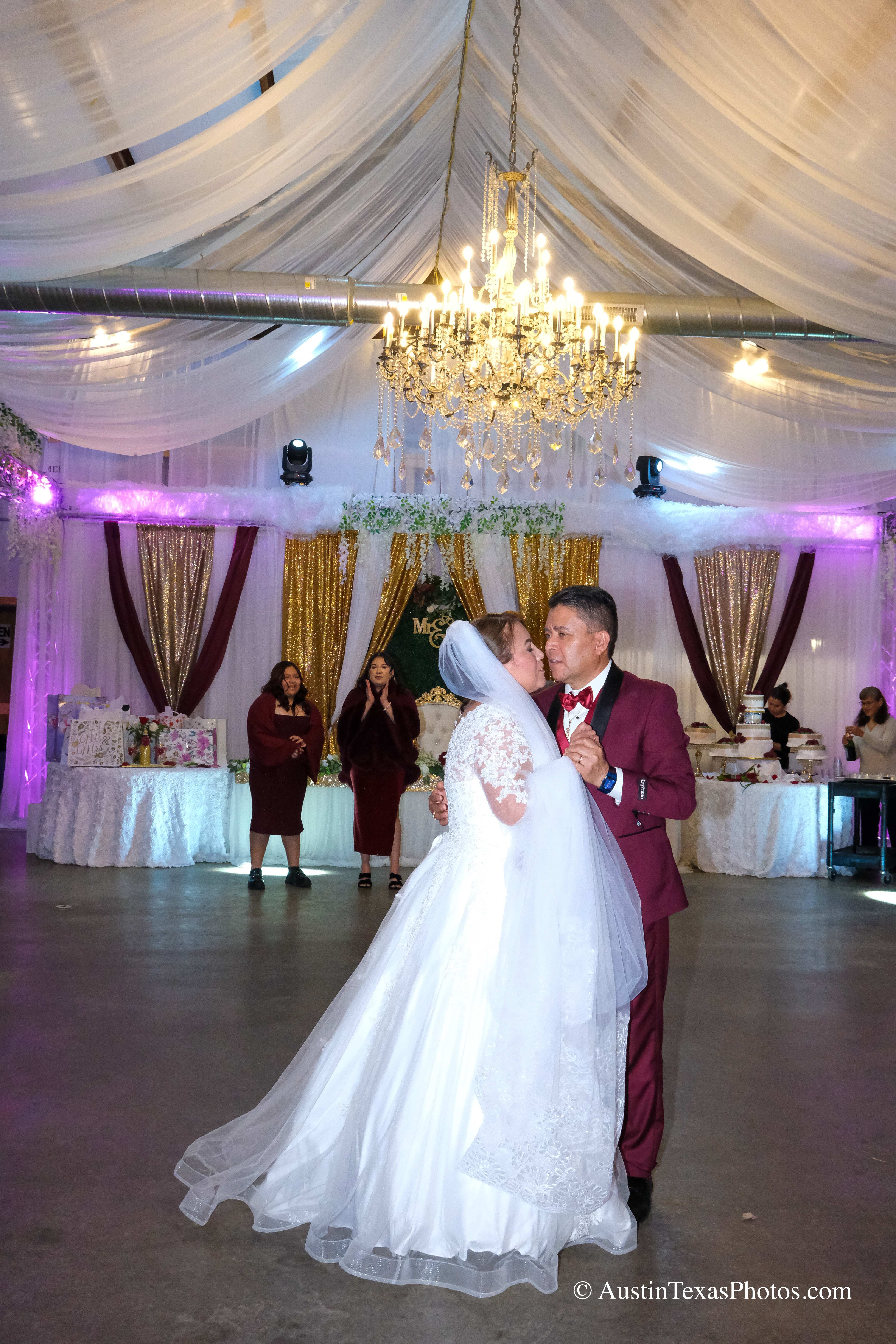Bride and groom kissing under reception lights at wedding celebration