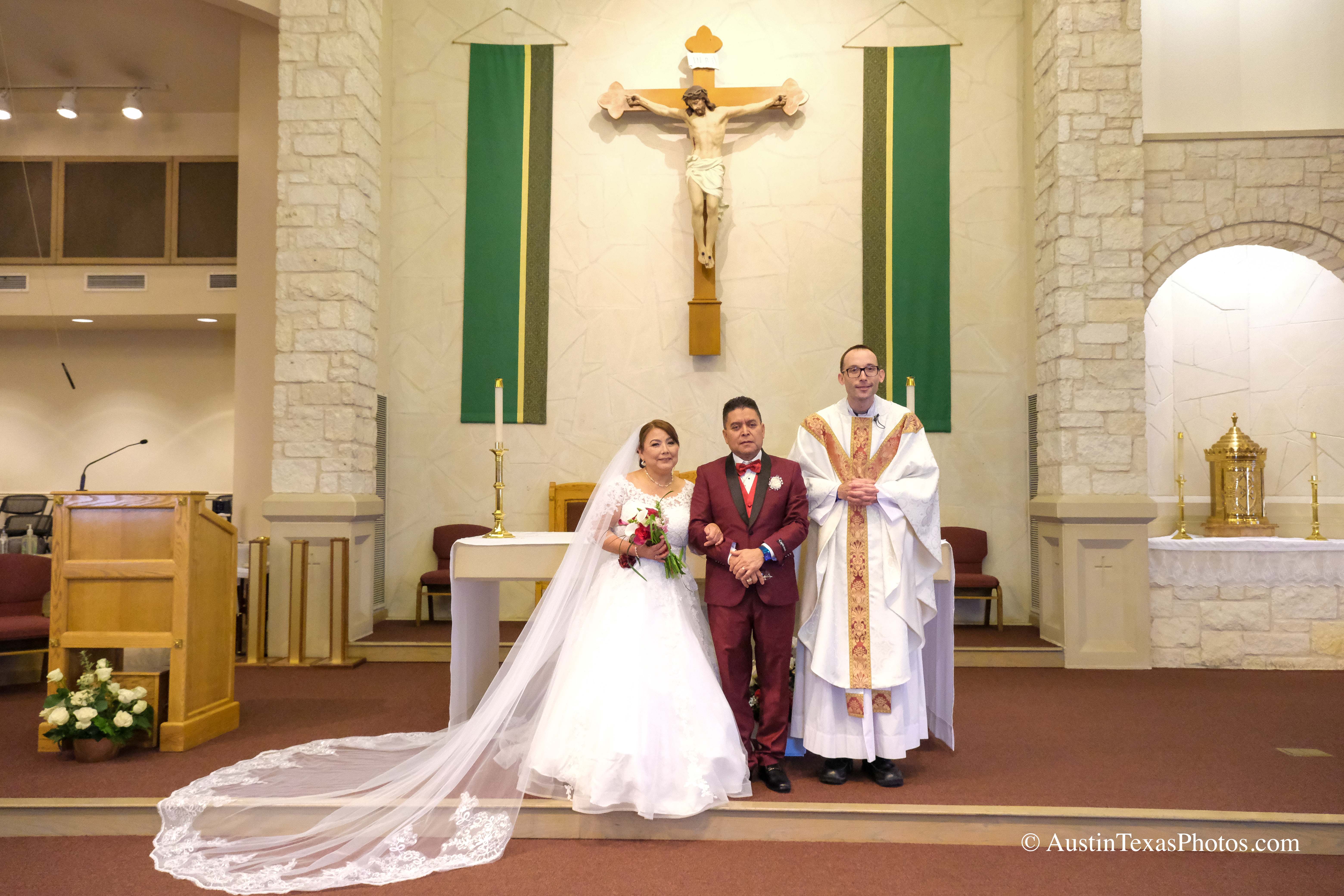 Bride and groom posing with priest at the altar after wedding ceremony