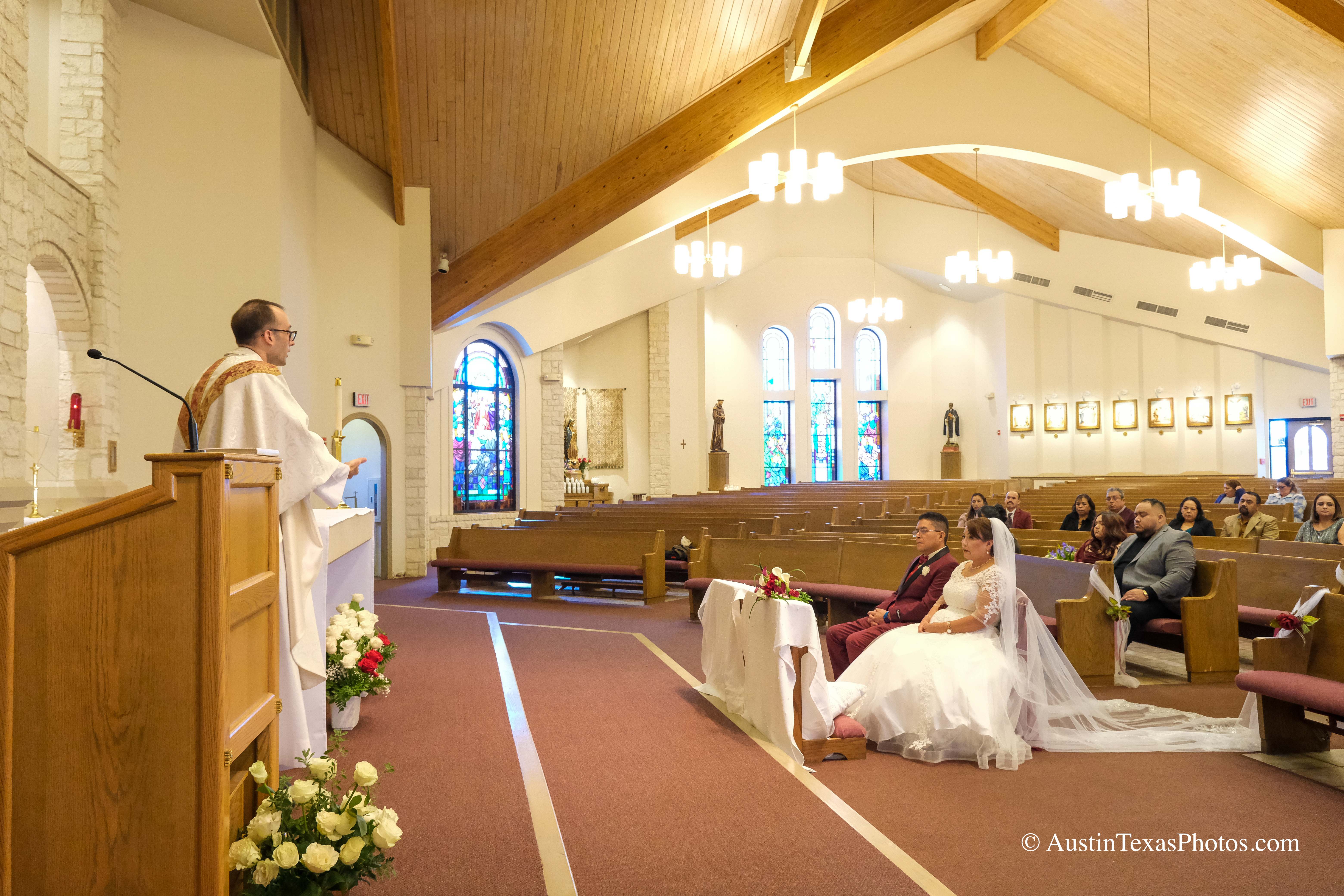 Bride and groom with priest during wedding ceremony at Santa Cruz Catholic Church