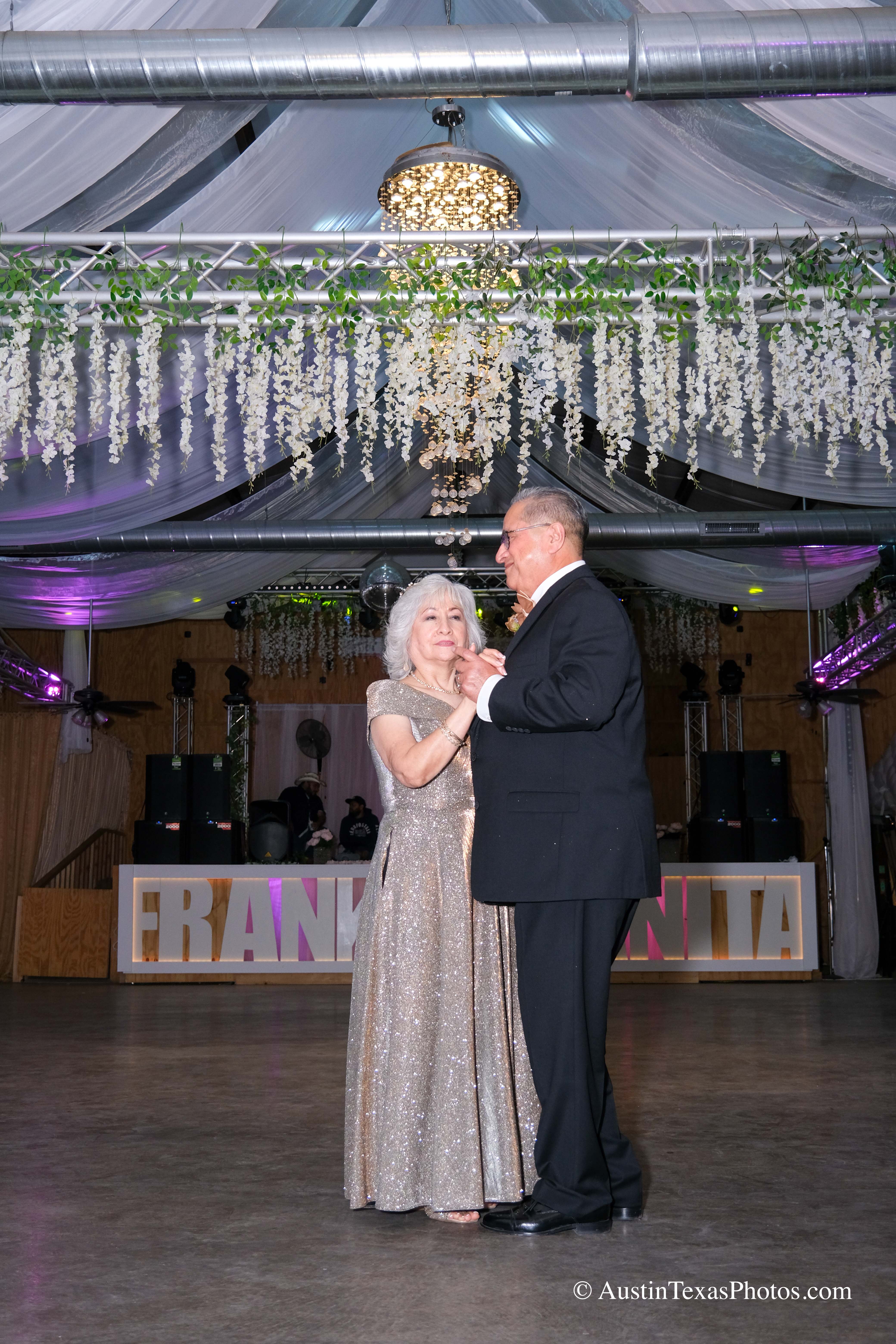 Bride and groom kissing under reception lights at wedding celebration
