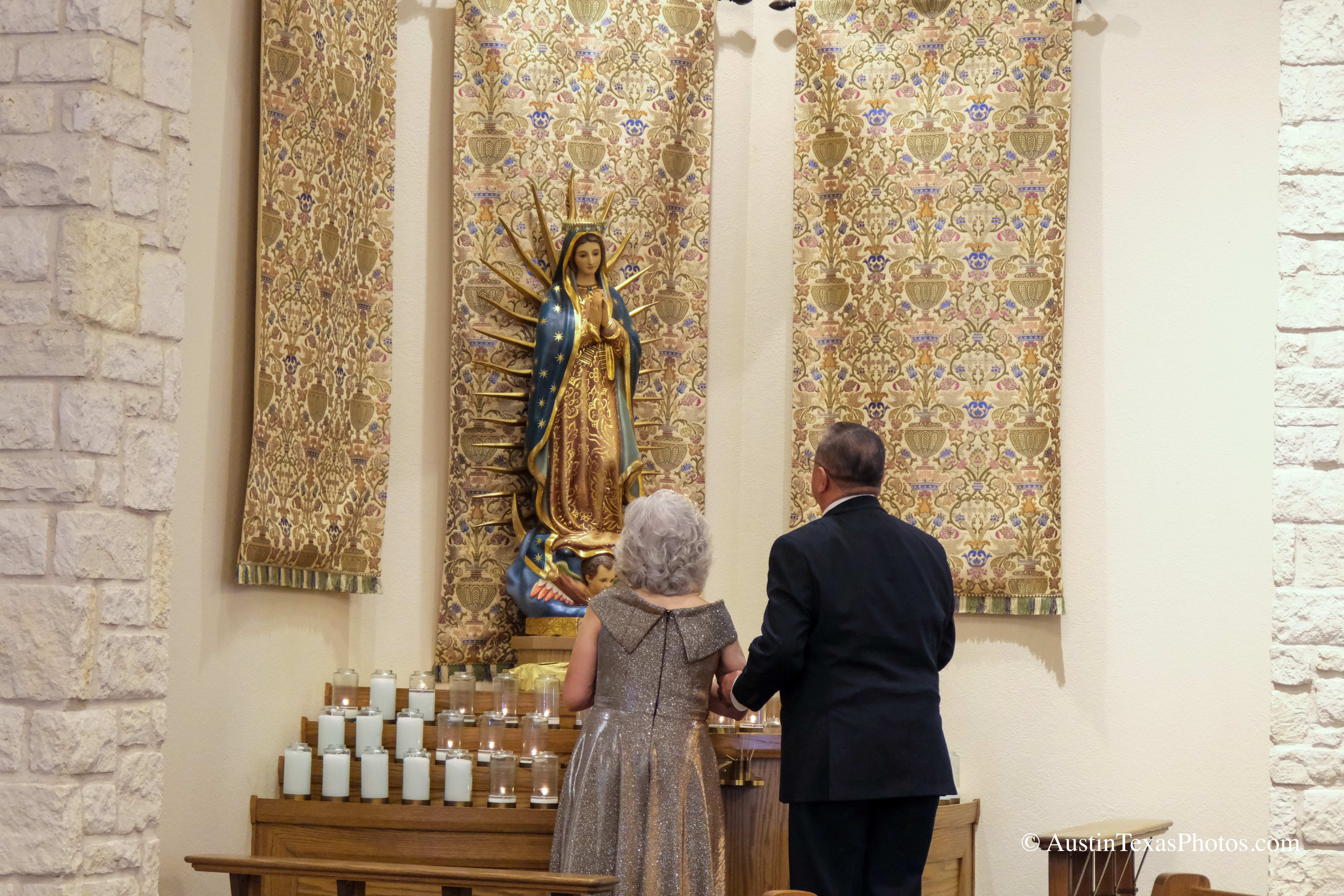 Bride and groom posing in front of Virgin Mary shrine at Santa Cruz Catholic Church