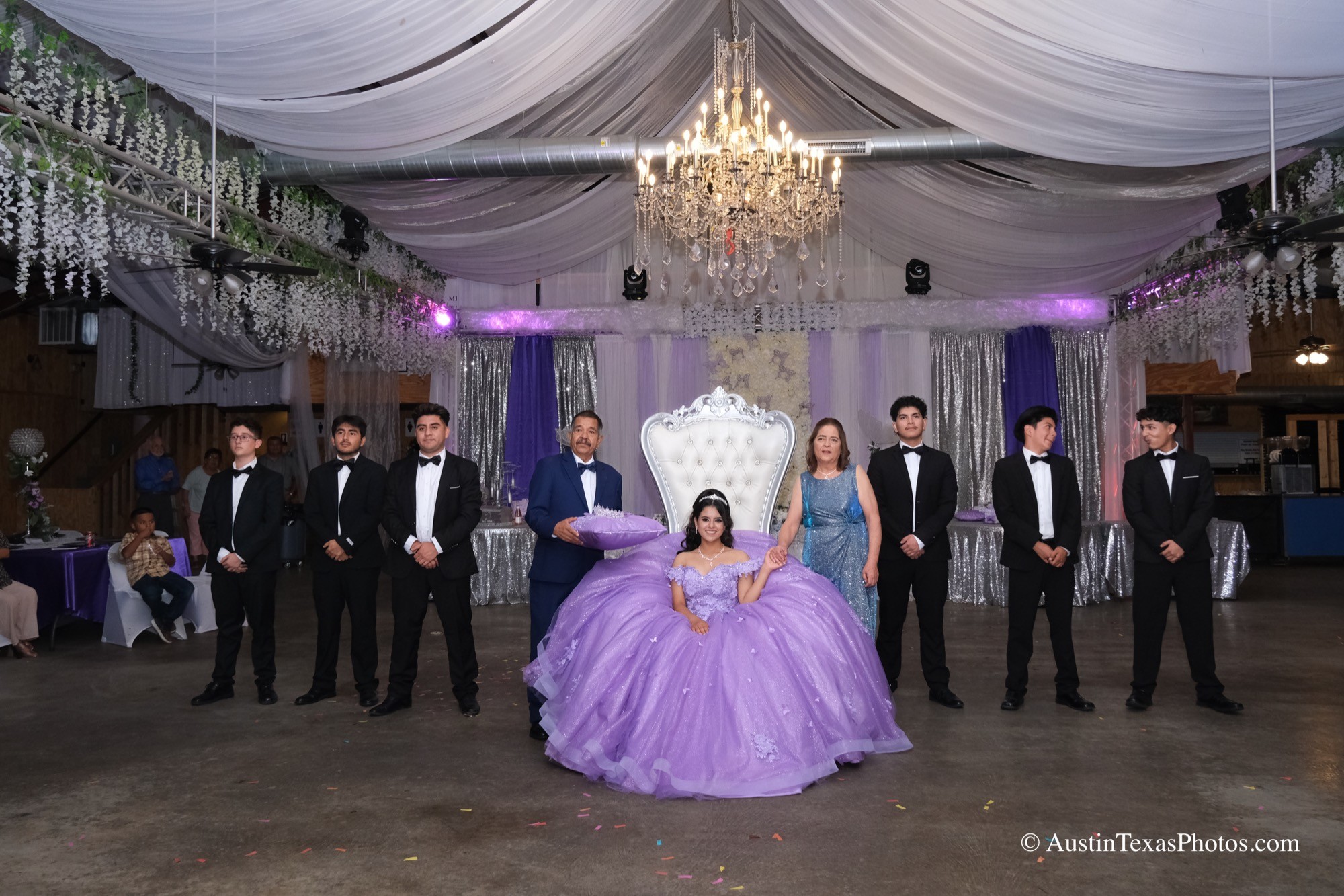 Quinceañera seated while chambelanes and grandparents present the tiara crown gift