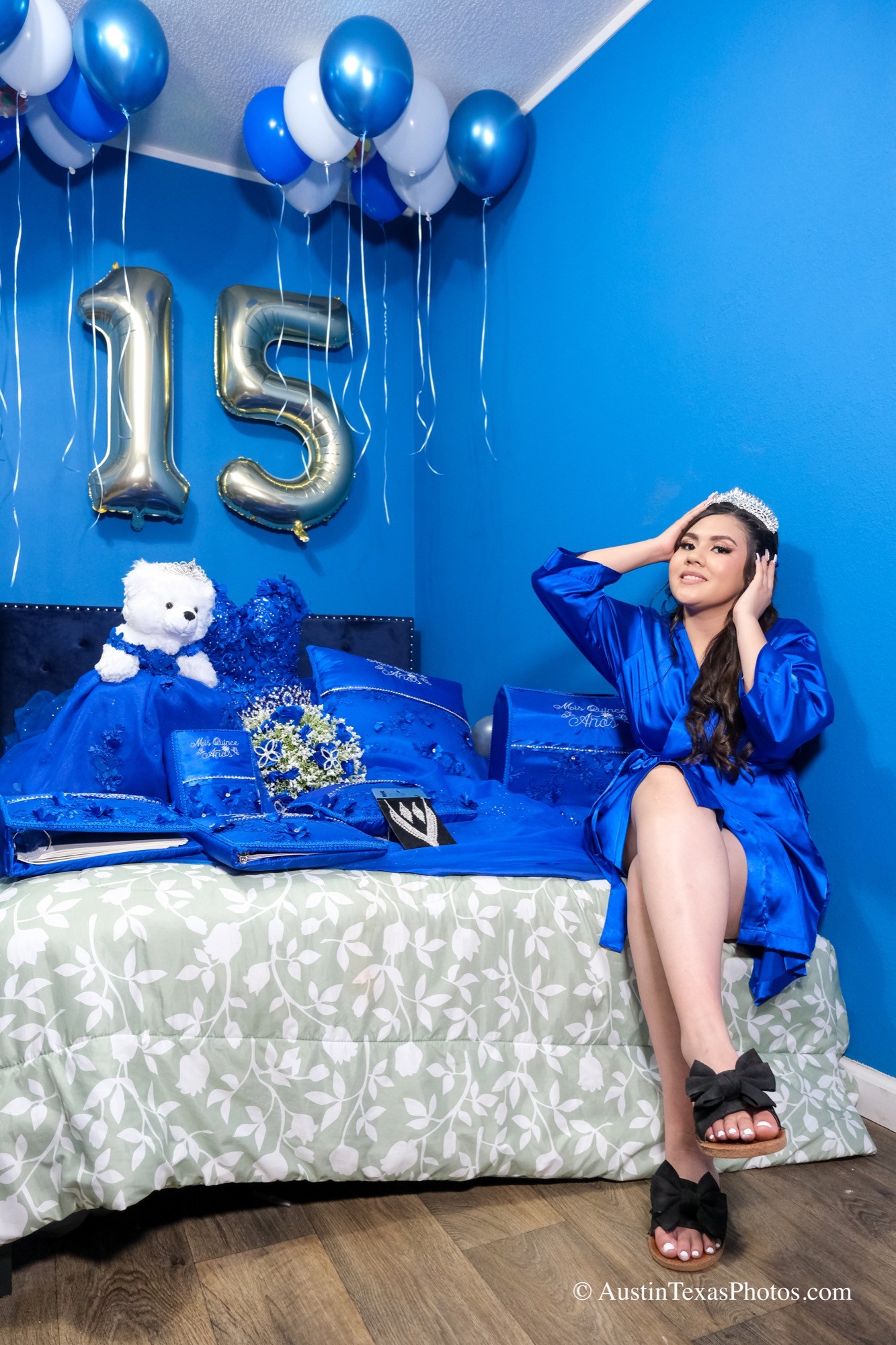 Quinceañera posing with balloons, a book, and her doll before the event
