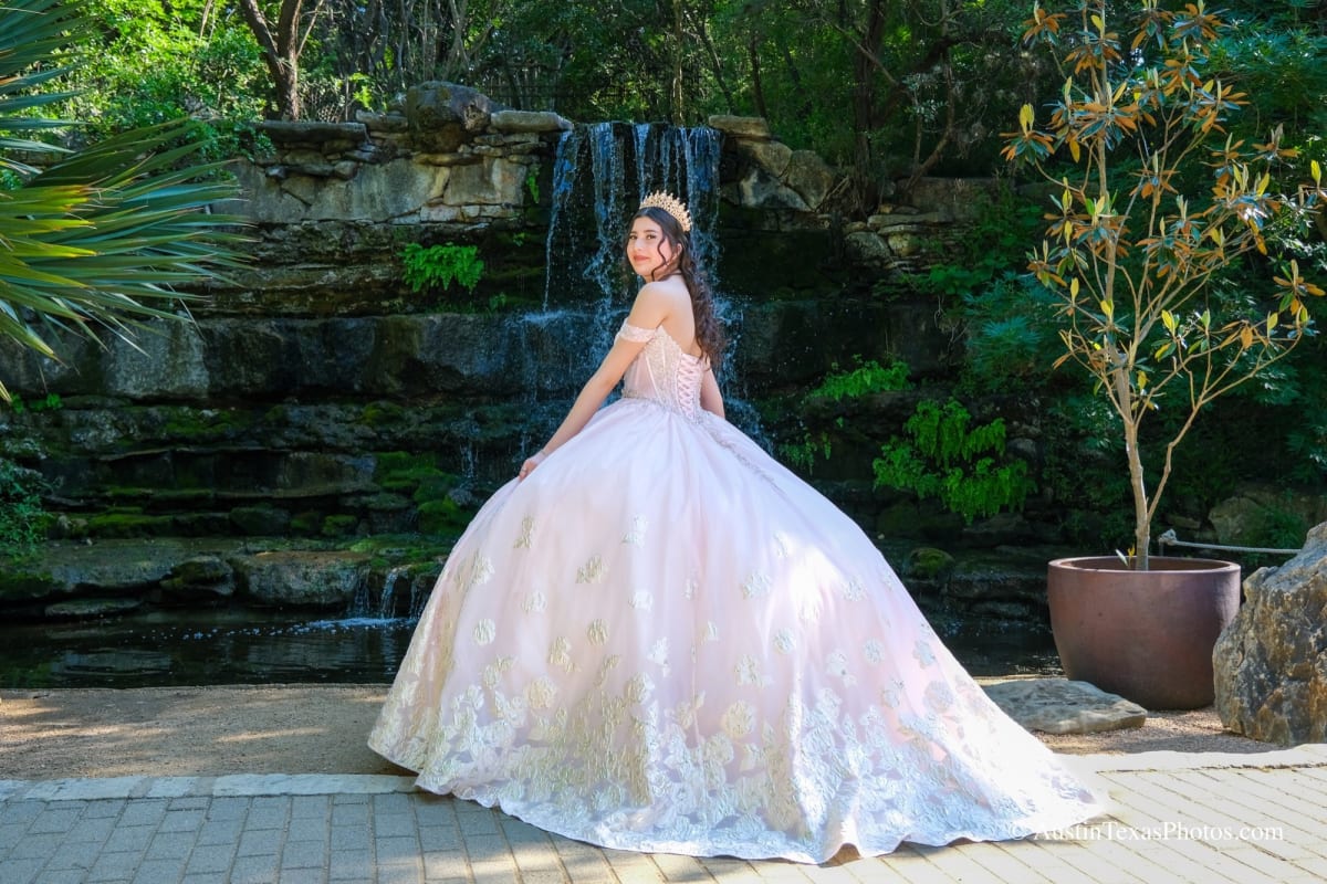 Quinceañera pre-shoot portrait in a pink ball gown at a garden waterfall in Austin, Texas
