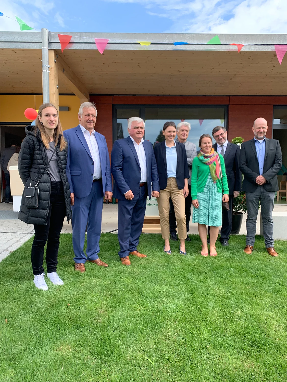 Romina Kieslinger GHIW, stellv. Landrat Bernhard Krempl, Bürgermeister Ludwig Waas, Kindergartenleiterin Brigitte Murrer, Christian Illner GHIW (hinten), Pfarrer Kellermann (hinten), Frau und Herr Kiendl (Außengestaltung) (v.l.n.r.)