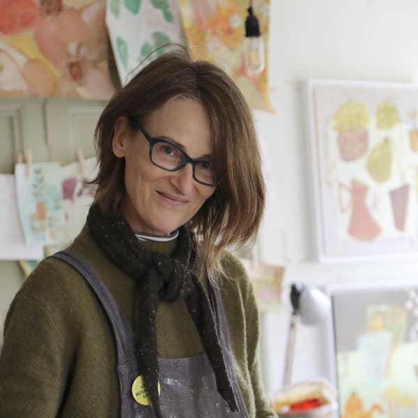 Brigitte Girling Artist smiling as she paints in her home studio surrounded by her joyful artworks