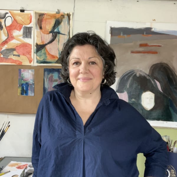 Hilde Pollet in her art studio, standing in front of intuitive expressive oil paintings