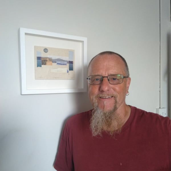 Geoff Litchfield next to a one of his framed collages