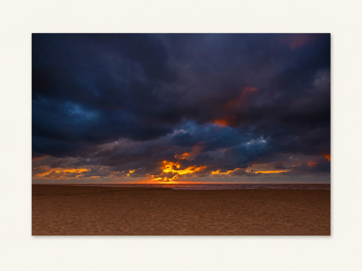 Dramatic sunset light beneath dark clouds over the coast