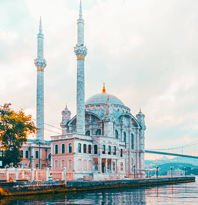 Ortakoy Mosque on the Bosphorus waterfront in Istanbul with two minarets and blue dome reflected in water