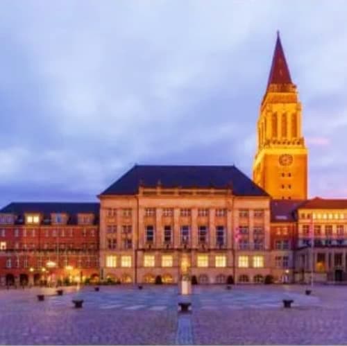 Illuminated town hall and church tower at dusk in Kiel's central square