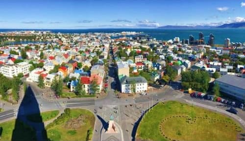 Aerial view of Reykjavik cityscape with colorful residential buildings, streets, and bay with mountains in distance