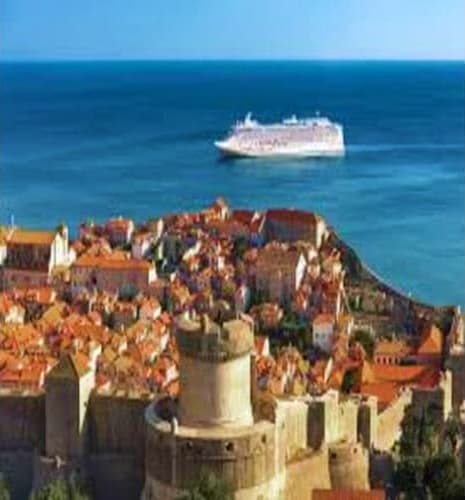 Aerial view of Dubrovnik's walled old town with fortress tower overlooking Adriatic Sea and cruise ship in distance