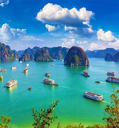 Halong Bay with limestone karsts, turquoise waters, and traditional boats under blue sky with white clouds