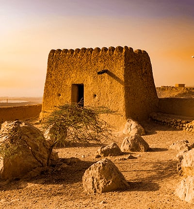 Ancient stone watchtower at sunset in the desert landscape of Ras al Khaimah, UAE, with rocky terrain and golden sky