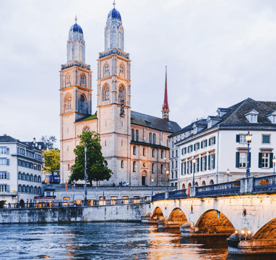 Gross Münster church with twin spires and Münsterbrücke stone bridge over Limmat River in Zurich's historic Old Town