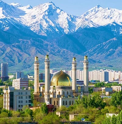 Islamic mosque with golden dome in Almaty city center with snow-capped mountains in background