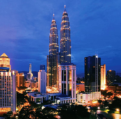 Petronas Twin Towers illuminated at dusk in Kuala Lumpur skyline with surrounding buildings and cityscape