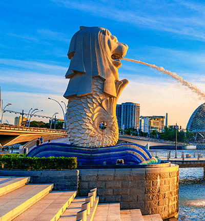 Merlion statue in Marina Bay Singapore with water fountain, modern buildings and blue sky