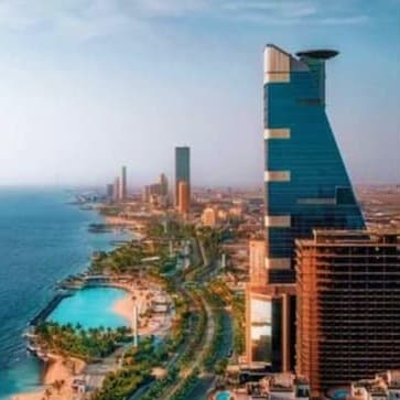 Aerial view of Jeddah's coastal skyline with modern high-rise buildings, sandy beaches, and turquoise swimming pool along the
