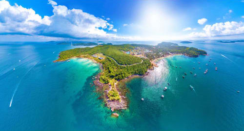 Aerial view of Phu Quoc island with turquoise waters, white sandy beaches, forested coastline and anchored boats