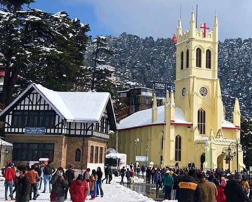 Snow-covered Shimla town square with Christ Church and Tudor-style buildings, tourists walking in winter holiday scene