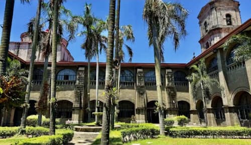 Historic Spanish colonial courtyard with palm trees and stone architecture in Manila