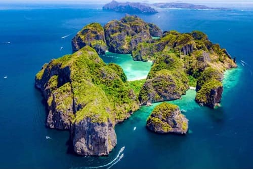 Aerial view of Phi Phi Islands in Krabi with turquoise lagoon, limestone cliffs and lush vegetation surrounded by blue sea.