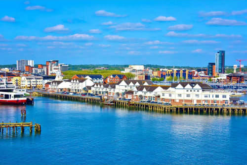 Southampton waterfront with white buildings, cruise ships, and blue harbor water under clear sky