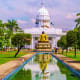 Golden Buddha statue with reflecting pool in front of white-domed parliament building surrounded by green grounds in Colombo