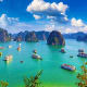 Halong Bay with limestone karsts, turquoise waters, and traditional boats under blue sky with white clouds