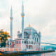 Ortakoy Mosque on the Bosphorus waterfront in Istanbul with two minarets and blue dome reflected in water